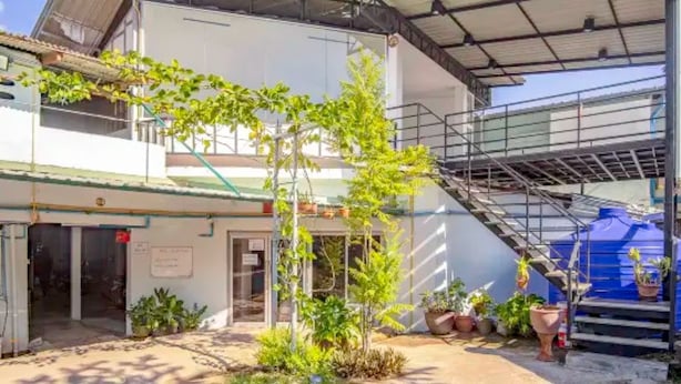 Un edificio con un acceso cubierto, una escalera y plantas en macetas.