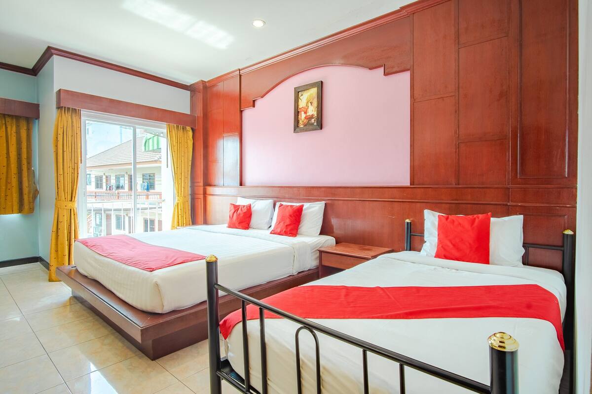 Een hotelkamer met twee bedden, een groot raam en uitzicht op gebouwen.