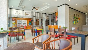 Un restaurant moderne avec des chaises et des tables en bois, un bar et un ventilateur de plafond.