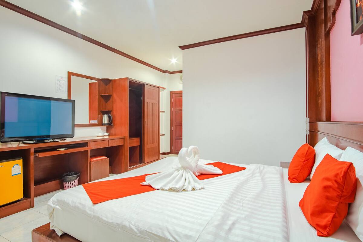 Een hotelkamer met een bed, een televisie, een bureau en een kledingkast.