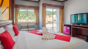 Une chambre d’hôtel avec un grand lit, une télévision et un balcon offrant une vue sur la ville.