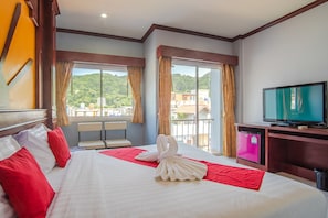 A hotel room with a bed, a TV, a small table, and a balcony with a view. - Art Mansion Patong Hotel (Patong)