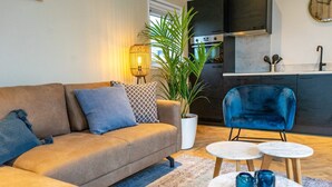 A modern living room with a sofa, a blue chair, and a small coffee table. - EuroParcs Texel (De Cocksdorp)