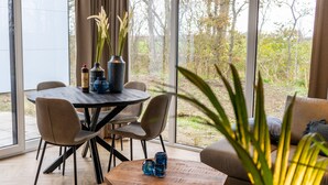 A modern dining area with a round table, chairs, and decorative vases. - EuroParcs Texel (De Cocksdorp)
