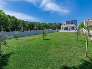 Una casa moderna con un patio amplio, fachada blanca y techo plano.