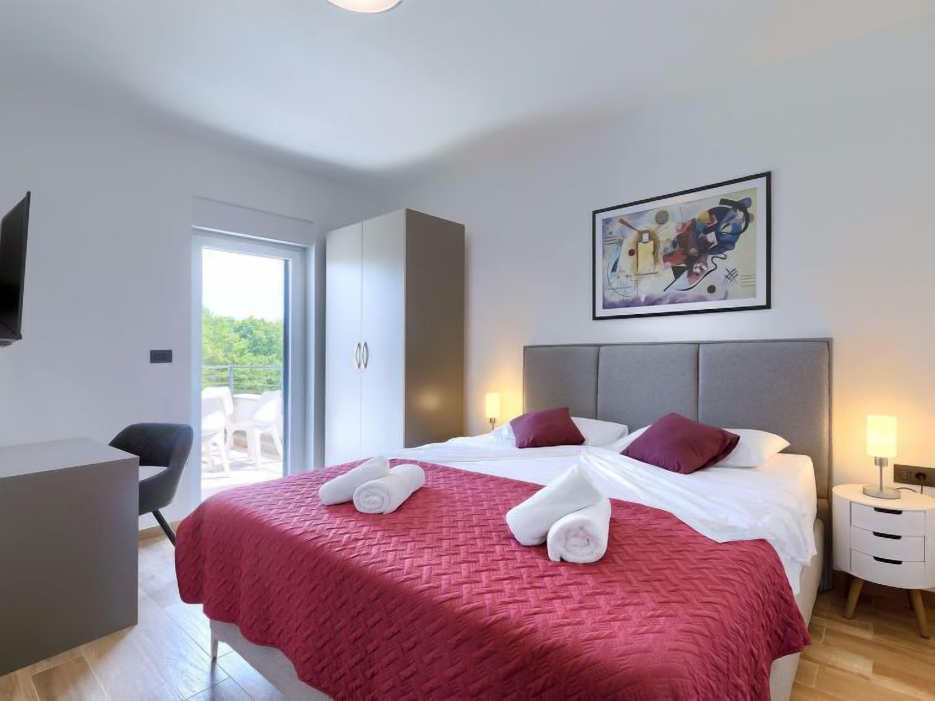 A modern hotel room with a large bed, a desk, and a view of the outdoors.
