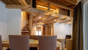 Een modern interieur met een houten trap, een eethoek met stoelen en een tafel, en een gezellige zithoek.