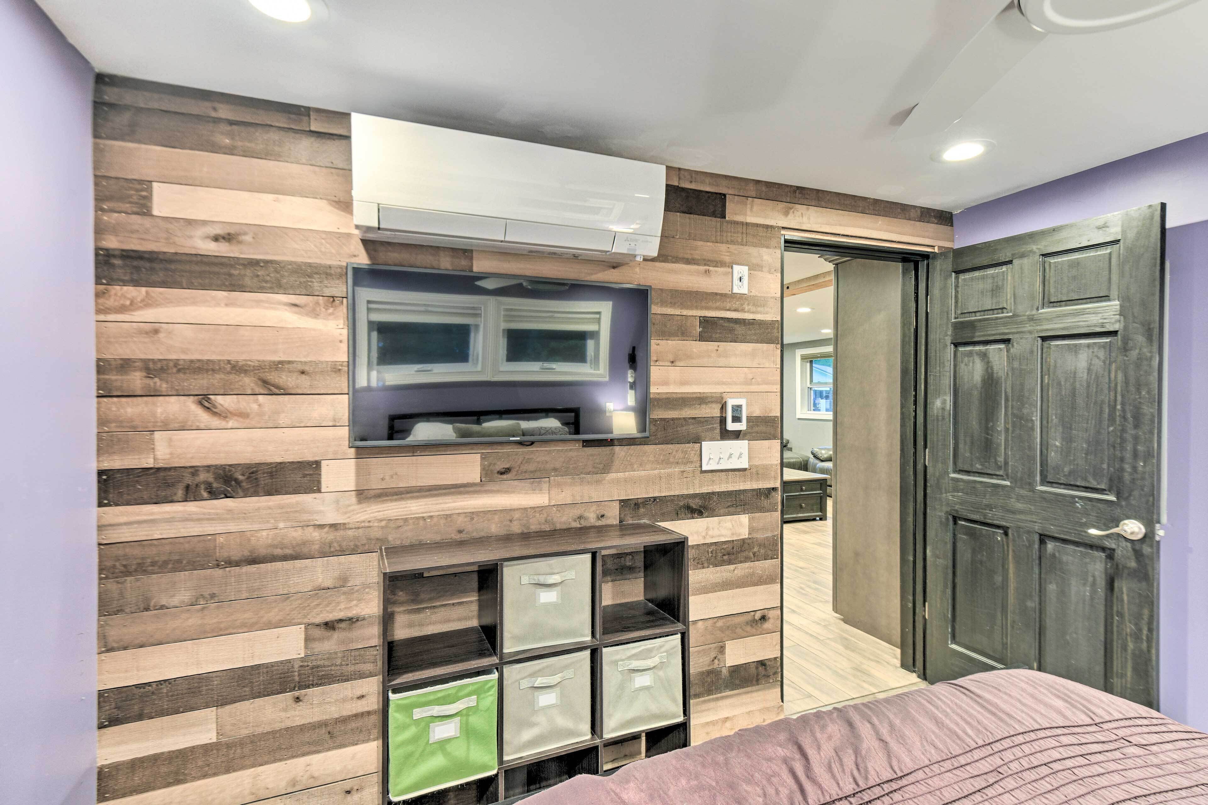 A modern room with a wooden wall panel, built-in storage, a flat-screen TV, and a door.