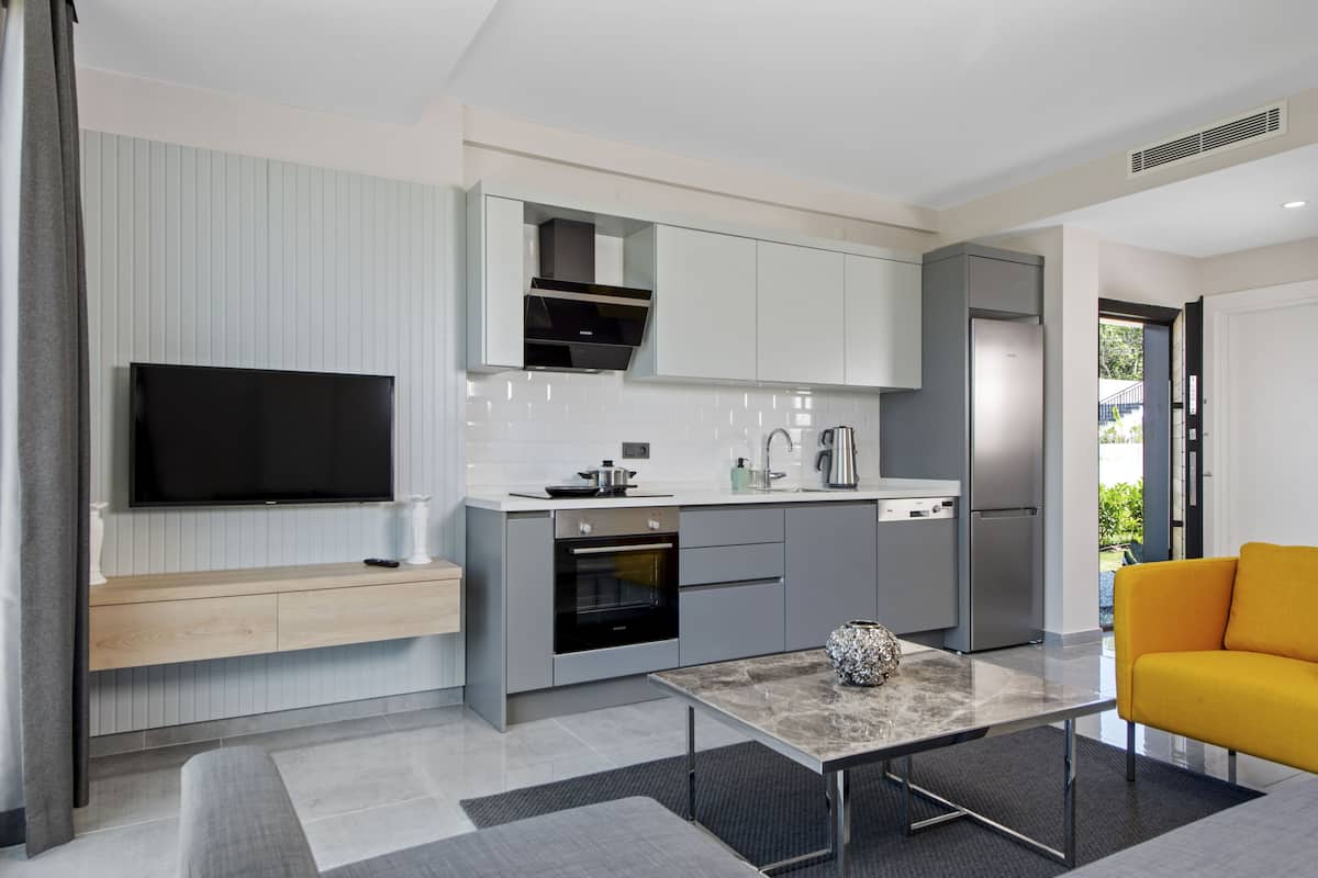A modern kitchen with built-in appliances, a flat-screen TV, and a dining area with a marble table.