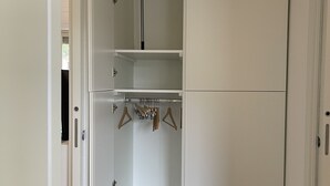 Un dressing avec plusieurs étagères et une tringle pour suspendre les vêtements.