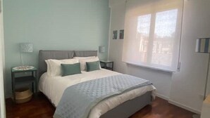 Une chambre à coucher avec un lit, des tables de chevet, une fenêtre et une vue sur l’extérieur.