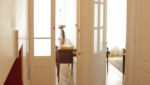 A hallway with wooden flooring, white doors, and a ceiling light fixture. - Romantic Design Apartment (Barcelona)