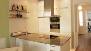 A modern kitchen with white cabinets, stainless steel appliances, and a marble countertop. - Romantic Design Apartment (Barcelona)