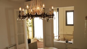 A dining area with a chandelier, a table with a glass, and a view of the outdoors. - Romantic Design Apartment (Barcelona)