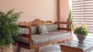 A wooden bench with striped cushions, a potted plant, and a vase with flowers. - Villa Maria (Zakynthos)