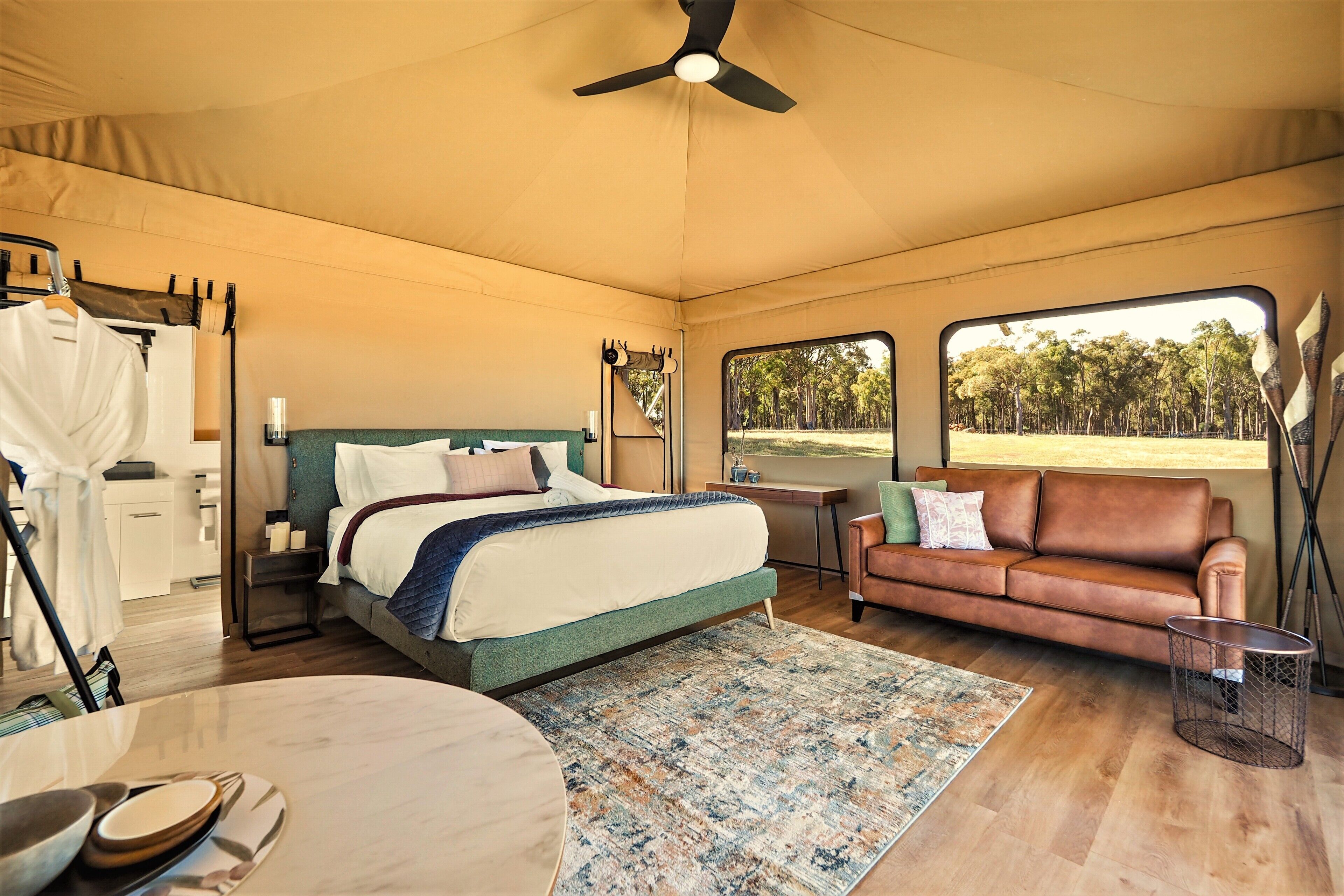 A spacious bedroom with a bed, a sofa, a dining table, and a view of the outdoors.