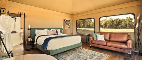 Un dormitorio amplio con cama, sofá, mesa de comedor y vistas al exterior.