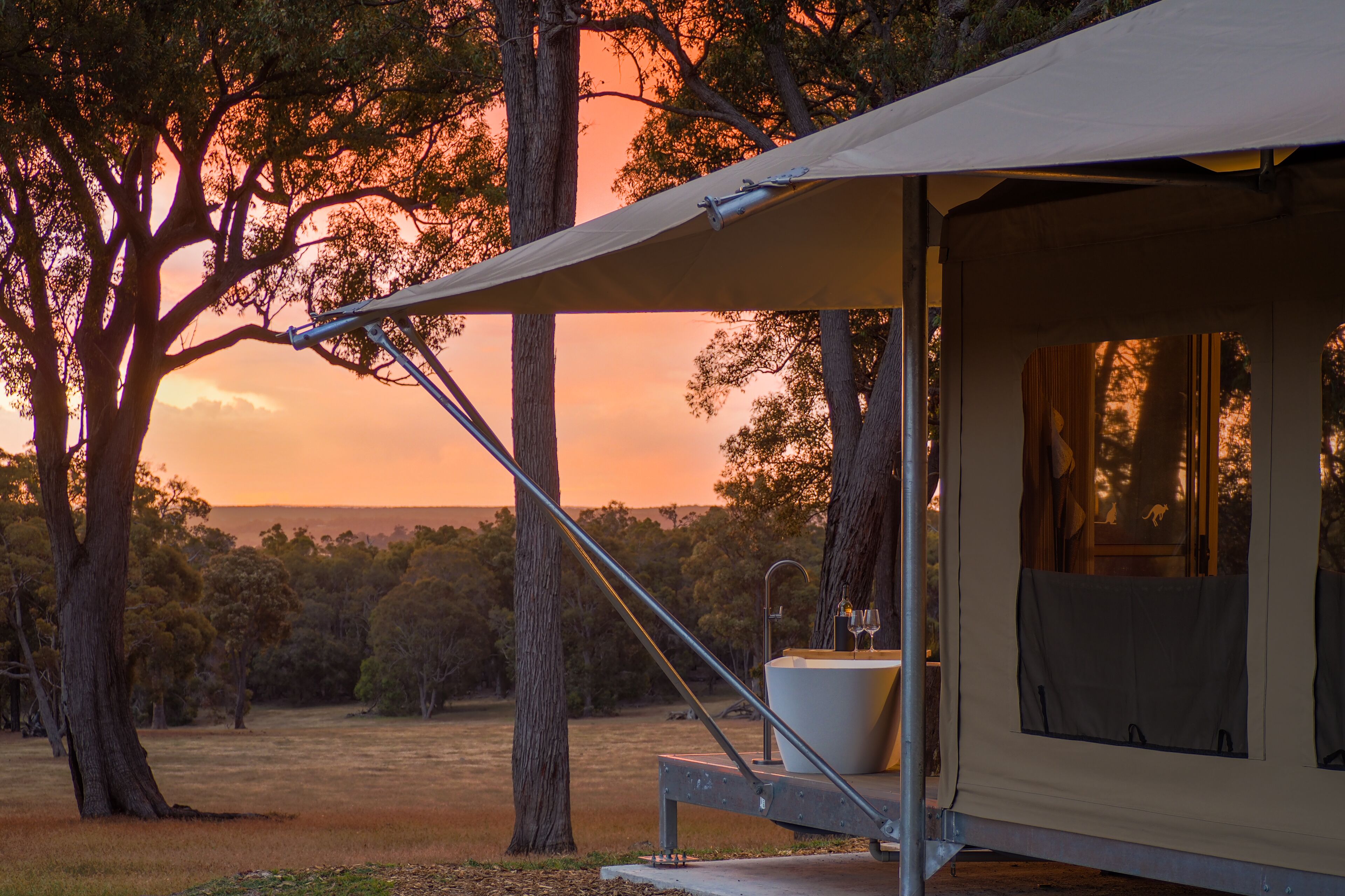 A tent with a bathtub and a sink, surrounded by trees.