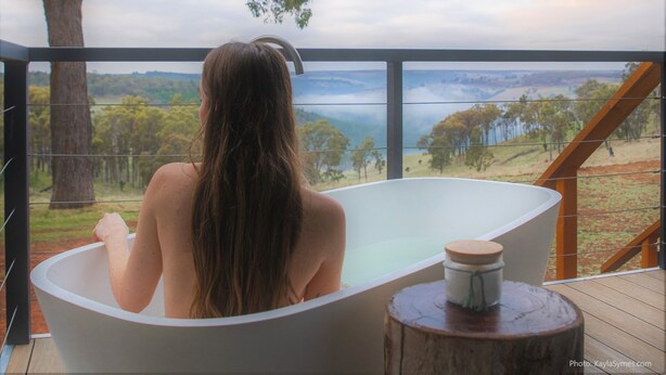 Eine Person in einer Badewanne mit Blick auf eine Landschaft.