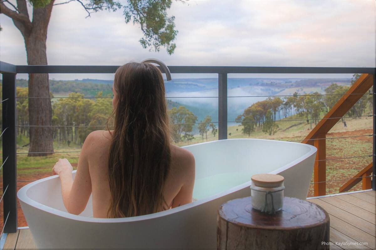 A person in a bathtub with a view of a landscape.