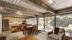 A modern kitchen with wooden cabinets and a dining area with a wooden table and chairs. - Chateau Eau Claire Unit 8 | Riverfront Condo, Walking Distance to Town (Aspen)