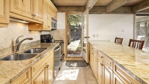 A kitchen with wooden cabinets, granite countertops, a double sink, and a built-in stove. - Chateau Eau Claire Unit 8 | Riverfront Condo, Walking Distance to Town (Aspen)