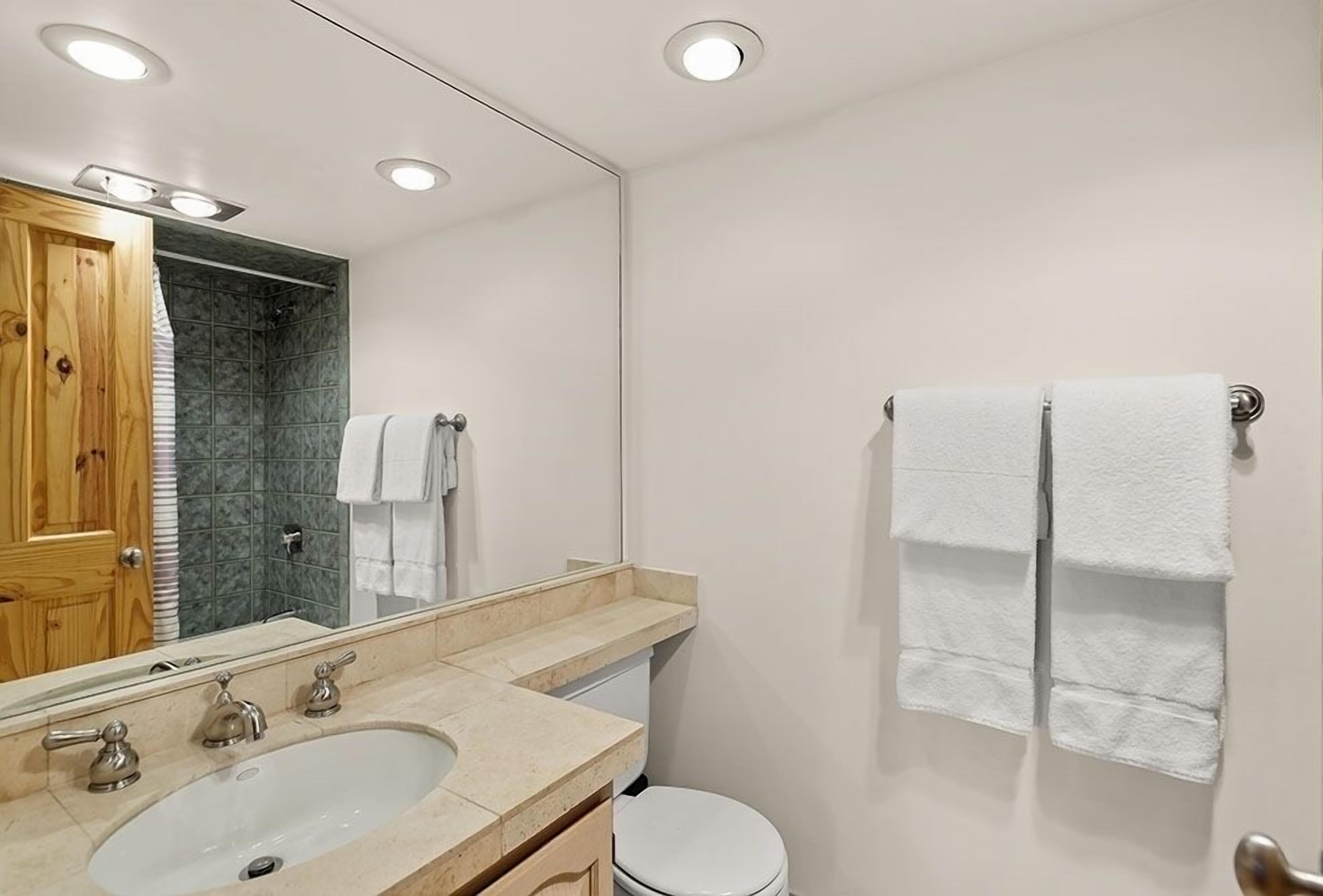 A bathroom with a sink, mirror, and two towels hanging on the wall.