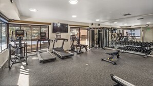 Un gimnasio con cintas de correr, elípticas, banco de pesas y pesas sueltas.