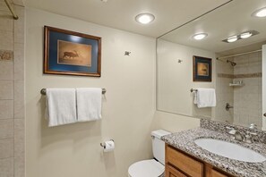 Ein Badezimmer mit Toilette, Waschbecken und Spiegel. An der Wand hängen zwei Bilder in Rahmen.