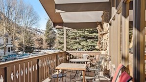 Un balcon avec des sièges pour l’extérieur, un mur en pierre et une vue sur une colline enneigée.