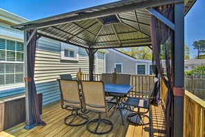 A covered outdoor patio with a table and chairs, wooden deck, and a metal roof structure. - Walk to Swift's Beach! Classic Cottage w/ Deck (Wareham)