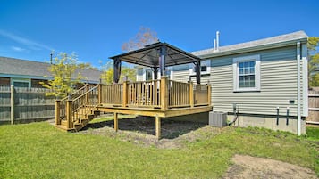 A wooden deck with a covered area, a fenced yard, and a house with a chimney.