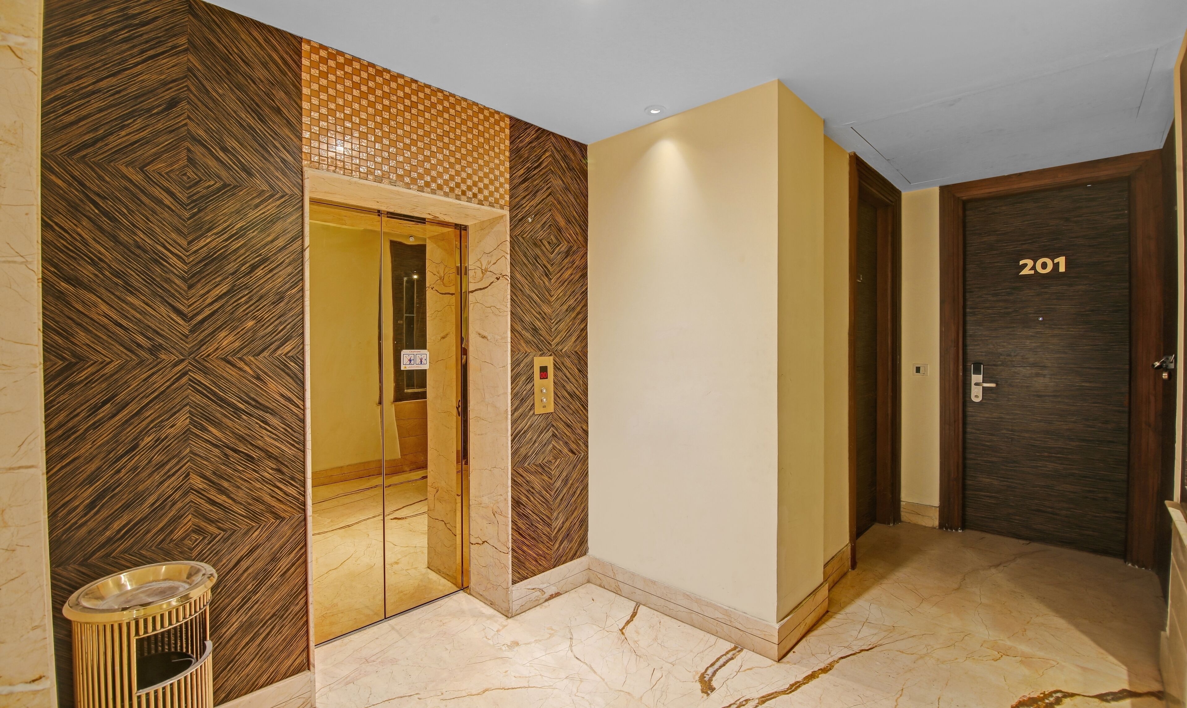 A hotel corridor with a marble floor, a wooden door labeled 201, and a mirrored elevator door.