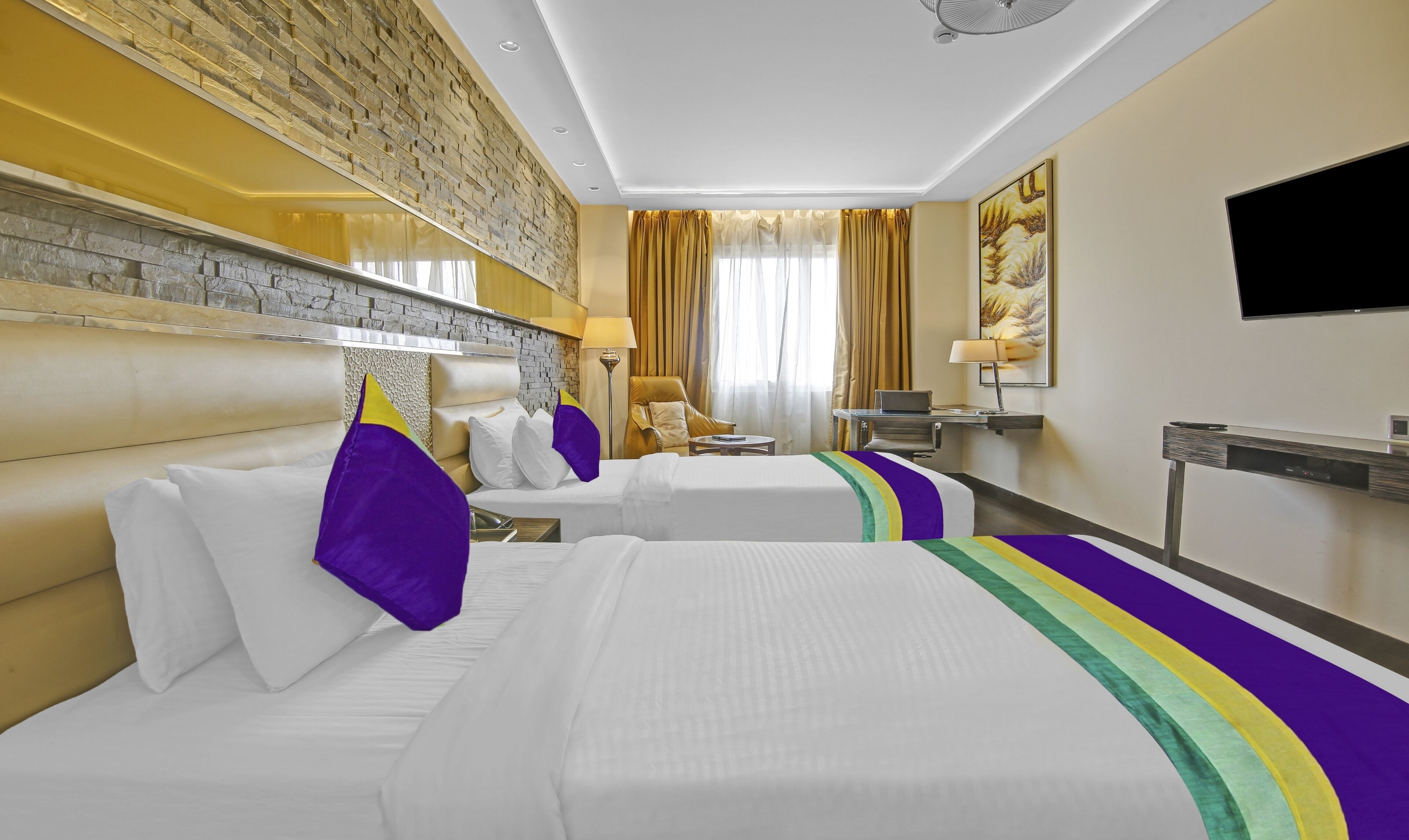 Habitación de hotel con dos camas, un escritorio, una silla, un televisor y un amplio ventanal con cortinas.