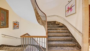 A curved staircase with marble steps and a wooden handrail, leading to a landing with a glass door. - Treebo Premium Arista (Mohali)
