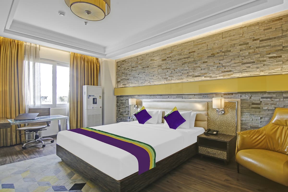 Una habitación de hotel con una cama grande, un escritorio, una silla y un sillón de cuero.