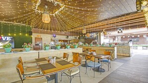A restaurant with a bar area, wooden tables and chairs, and hanging string lights. - Treebo Premium Arista (Mohali)