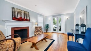Una sala de estar con chimenea, una mesa de comedor y una silla azul.