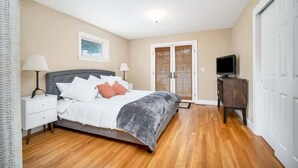 Un dormitorio con cama, mesitas de noche, un mueble para televisor y un armario con puertas correderas.
