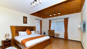 Een ruime slaapkamer met een groot houten bed, een klein rond tafeltje en een stoel.