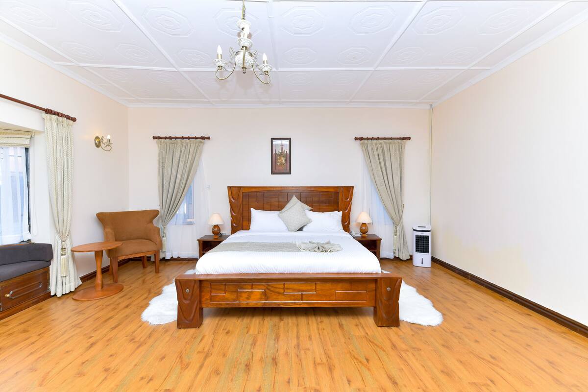 Ein Schlafzimmer mit einem hölzernen Bett, einem Sessel, einem kleinen Tisch und einem Heizgerät.