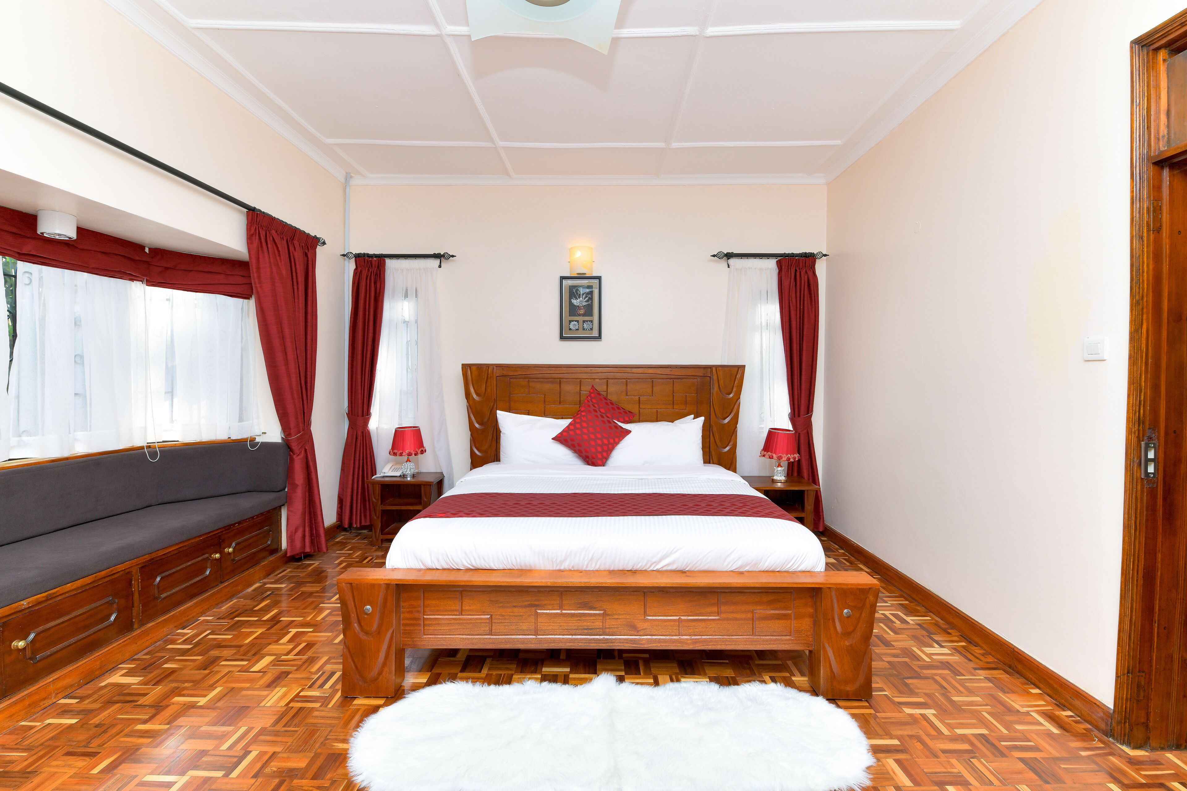 A bedroom with a wooden bed, a sofa, and a white furry rug.