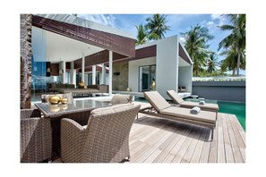 A modern outdoor pool area with lounge chairs and a dining table.