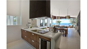 A modern kitchen with a large island, a dining area with a view, and a spacious living area. - Beachfront Villa . Private Beach & Pool. 3 bedrooms.  Housekeeper included . (Koh Samui)