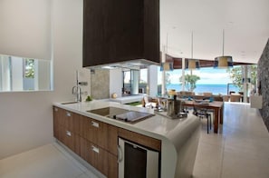A modern kitchen with a large island, a dining area with a view, and a spacious living area. - Beachfront Villa . Private Beach & Pool. 3 bedrooms.  Housekeeper included . (Koh Samui)