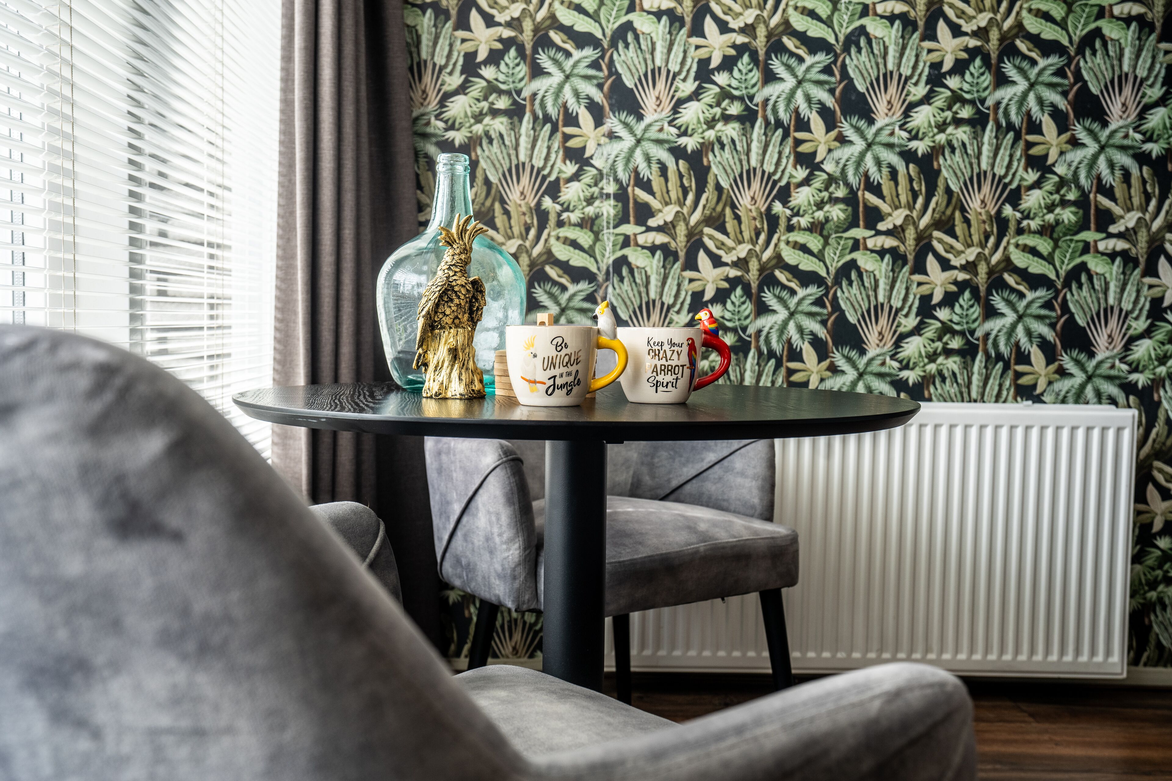 A room with a round table, two chairs, a decorative bottle, and a mug with text.