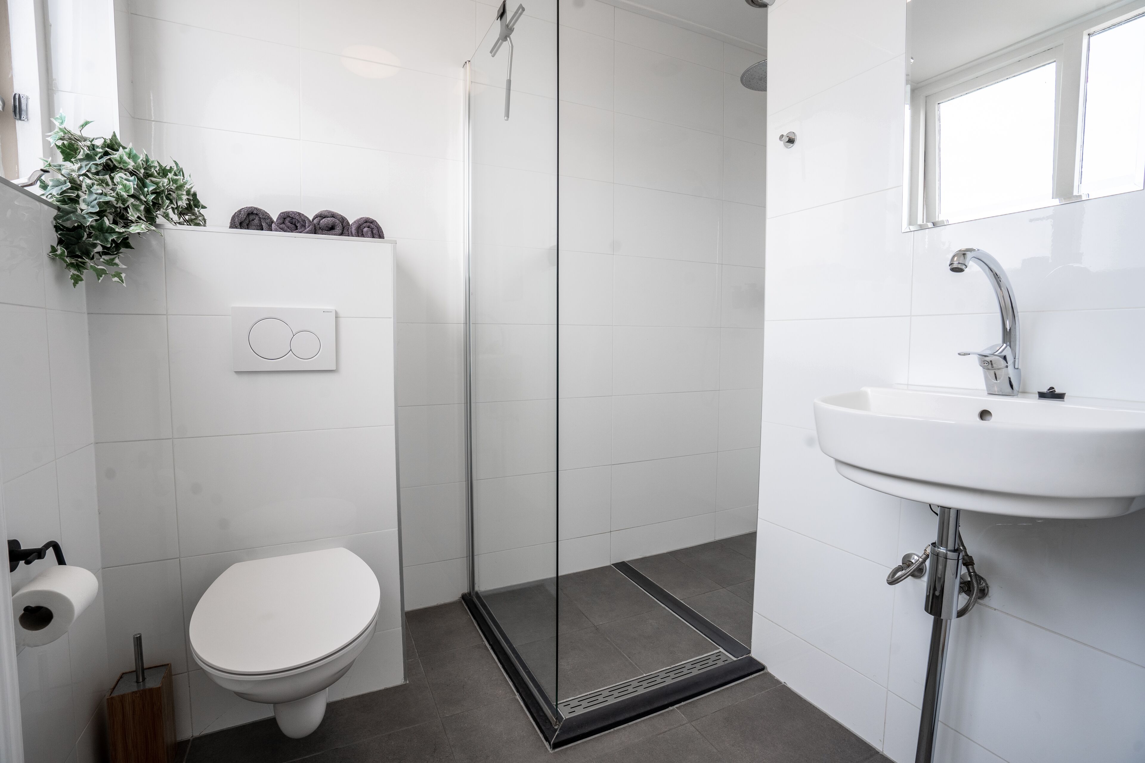A modern bathroom with a toilet, shower, and sink.