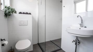 A modern bathroom with a toilet, shower, and sink.