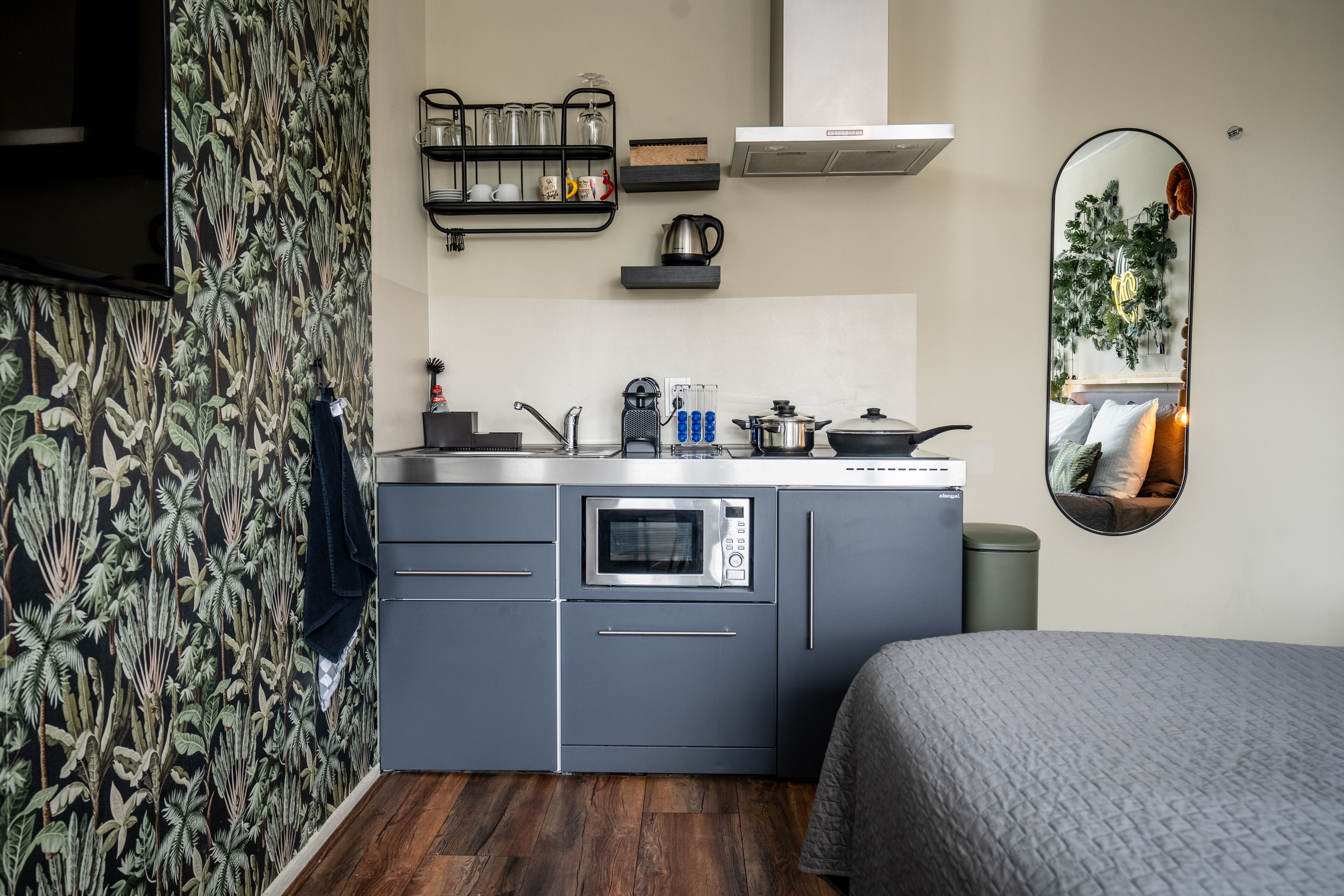Una cocina compacta con horno integrado, cafetera y hervidor en la encimera.