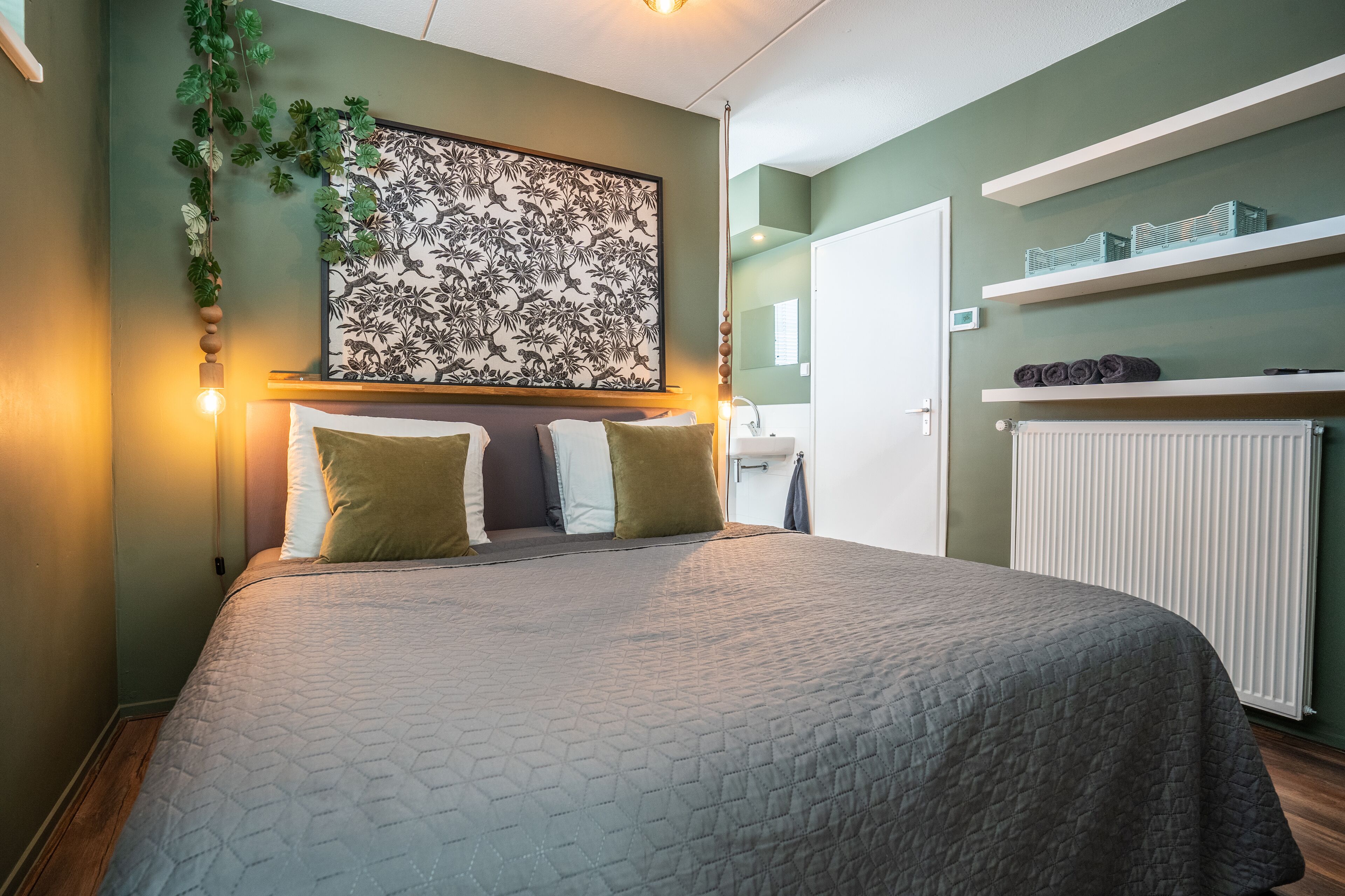 A neatly arranged bedroom with a bed, pillows, a wall-mounted artwork, and built-in shelves with items.